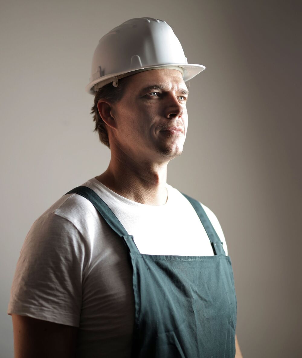 A plasterer in a white hard hat and overalls looking into the light